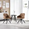 Two brown swivel chairs are placed in a living room setting with a small black table between them. Artwork hangs on the wall behind the chairs, and a floor lamp is visible in the background. Produktbild-Vorschau