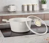 A modern kitchen counter with a white pot and lid on a black induction stovetop. In the background, there is a white toaster and canisters. Produktbild-Vorschau