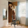 A woman is using a black step stool to reach into a closet. Voir les images du produit
