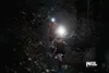 Two people running on a dark, wooded trail at night, illuminated by headlamps. Náhled obrázku produktu