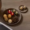 Several LED candles are arranged on a round tray with pinecones, set against a wooden surface. Produktbild-Vorschau