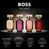 Four bottles of BOSS The Scent perfume are displayed on a reflective surface against a dark background, with text describing each fragrance below. Anteprima dell’immagine prodotto