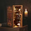 A miniature book nook designed to look like a bookstore, placed on a wooden surface next to a lit candle. Voir les images du produit