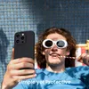A person wearing sunglasses and holding a phone case is lying down by a pool. Anteprima dell’immagine prodotto