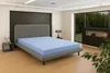 A bedroom with a bed, nightstand, and a large window overlooking a forest. Produktbild-Vorschau