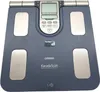A blue Omron Karada Scan body composition monitor scale is shown from a top-down perspective on a light gray background. Podgląd zdjęcia produktu