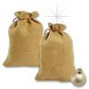 Two burlap gift bags with red drawstrings are shown, with a single gold Christmas ornament in the foreground. Produktbild-Vorschau