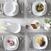 A table setting with multiple place settings, including plates, bowls, cutlery, and glasses, arranged on placemats. Produktbild-Vorschau
