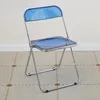 A blue folding chair on a patterned floor. Produktbild-Vorschau