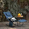 A blue rocking lounge chair with a pillow and a small side table with lemons and a drink, set on a wooden deck in a garden. Produktbild-Vorschau
