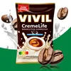 A product shot of VIVIL Creme Life Brasilitos Espresso candies, surrounded by milk splashes and coffee beans, with marketing text and nutritional information. Produktbild-Vorschau