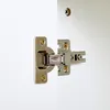 A close-up view of a cabinet hinge and screws on a white surface. Náhled obrázku produktu