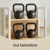 Four black kettlebells are displayed on two shelves of a white and wood-grain shelf unit. Produktbild-Vorschau