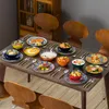 A dining table set with a complete 36-piece porcelain tableware set for 12 people, featuring plates, bowls, and serving dishes with a bohemian style pattern. The table is set with food, suggesting a meal is about to be served or has just been enjoyed. Produktbild-Vorschau