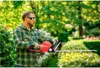A man is using an electric hedge trimmer in a garden. Produktbild-Vorschau