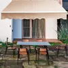 An outdoor patio scene with a table and chairs set up under a retractable awning. Anteprima dell’immagine prodotto
