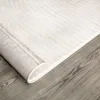 A close-up, angled view of a rolled-up rug on a wooden floor. Anteprima dell’immagine prodotto