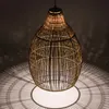 A hanging pendant light made of woven material, casting intricate shadows on the wall and floor. Produktbild-Vorschau