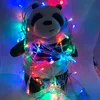 A stuffed panda toy is wrapped in colorful LED string lights. Náhled obrázku produktu