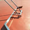 A close-up view of a tennis court sweeper on an orange tennis court. Podgląd zdjęcia produktu