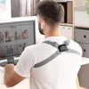 A man is sitting at a desk, looking at a computer screen, while wearing a posture trainer. Podgląd zdjęcia produktu