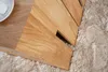 A close-up view of a wooden side table on a textured rug. Produktbild-Vorschau
