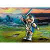 A toy knight figure holding a sword in a fantasy landscape with a castle in the background. Produktbild-Vorschau
