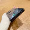 A hand holding a phone case with a magnetic ring on a wooden surface. Náhled obrázku produktu