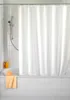 A white shower curtain hangs over a bathtub in a tiled bathroom. Náhled obrázku produktu