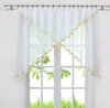 A white sheer curtain with gold trim is hung on a window. Produktbild-Vorschau