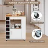 A white kitchen cart with a wooden top, featuring wine bottle storage and mug hooks, is shown in a kitchen setting. The image also highlights the cart's wheels and their locking mechanism. Podgląd zdjęcia produktu