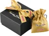 A black gift box with a gold ribbon and a gold drawstring pouch next to it. Anteprima dell’immagine prodotto