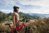 A person with a mountain bike on a grassy hill overlooking a valley. Anteprima dell’immagine prodotto