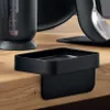 A black sponge holder sits on the edge of a wooden countertop. Náhled obrázku produktu