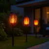Three solar-powered garden torches with a flame effect are lit up at night in a garden setting. Náhled obrázku produktu