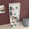 A white bookshelf with books and decorative items on a brown wall. Produktbild-Vorschau