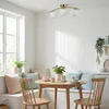 A dining nook with a built-in bench, a round wooden table, and chairs, illuminated by a ceiling light. Náhľad obrázku produktu
