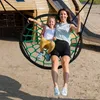 A mother and daughter are swinging on a large net swing in a playground. Voir les images du produit