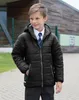 A young boy wearing a school uniform stands outside a building. Produktbild-Vorschau