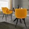 Two yellow velvet dining chairs are placed around a wooden dining table in a dining room setting.