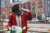 A person is drinking from a water bottle while standing next to a bicycle. Produktbild-Vorschau
