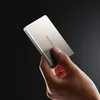 A hand holds a silver power bank against a dark background. Produktbild-Vorschau