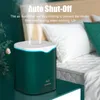A teal humidifier with a white top is shown on a teal table, with a bed in the background. Mist is coming out of the humidifier. Produktbild-Vorschau