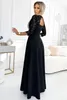 A woman wearing a black dress stands in a well-lit room with modern decor. Anteprima dell’immagine prodotto