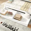 Close-up view of the drawers of a white daybed, showing folded clothes, a wooden box, and a small pillow. Produktbild-Vorschau