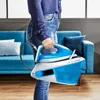 A person is holding a steam iron station in a living room setting. Produktbild-Vorschau