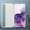 A white flip case for a Samsung Galaxy S20 Plus is shown open, revealing the phone's screen displaying a floral wallpaper. The background is a plain blue-gray. Podgląd zdjęcia produktu