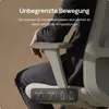 A person is sitting in an office chair, demonstrating the armrest features. Podgląd zdjęcia produktu