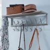 A wall-mounted coat rack with a shelf above it, holding a basket and a hat. Several bags and a scarf are hanging from the hooks below. Produktbild-Vorschau