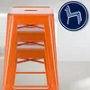 An orange metal bar stool is shown in a studio setting with a white floor and background. A circular logo with a stylized chair icon is in the upper right corner. Náhľad obrázku produktu